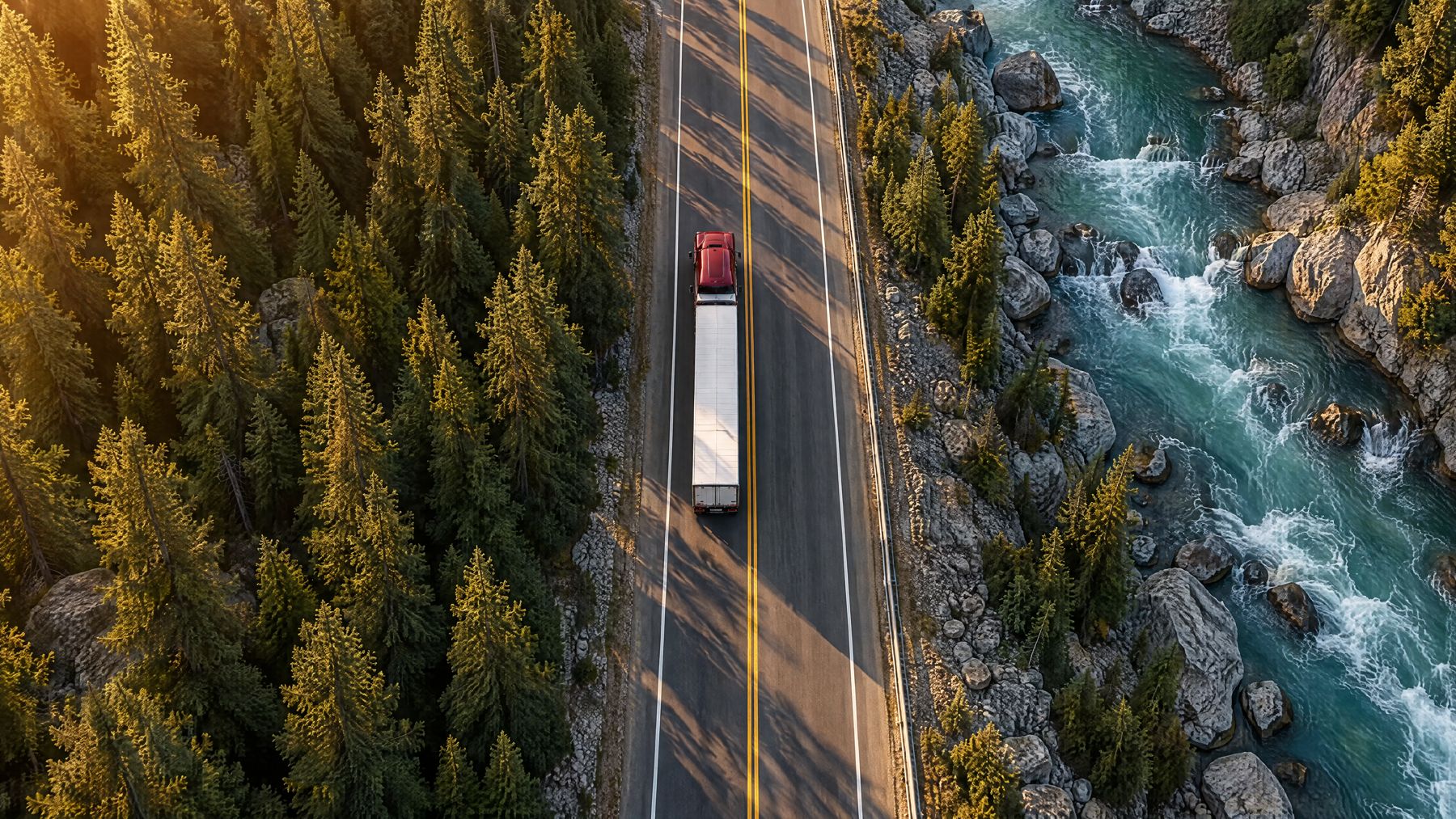 A Miracle Mile truck on a forest highway beside a river